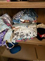 Folded assorted garments on shelf, patterned fabrics visible