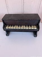 Front view of dark wood toy piano showing keyboard and legs