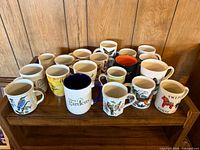 Overview of twenty assorted mugs arranged on shelf