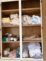 Cabinet shelves with folded flannel sheets, socks, towels and other textiles
