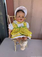 Full view of doll seated on chair showing both items and overall wear