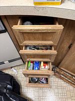 Stack of four open kitchen drawers showing assorted utensils and cutlery
