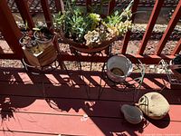 Overall view of three metal stands with planters, succulents and rocks