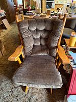 Front view of wooden glider rocking chair with brown tufted cushions