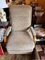 Front view of beige upholstered recliner with wood armrests