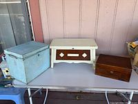 Three storage items: blue metal box, white and brown Swedish storage stool, brown wooden box