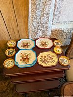 group shot of five butterfly-decorated metal trays and six wicker-sided butterfly coasters on nesting tables