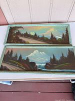 Both rectangular framed landscape artworks side by side on table