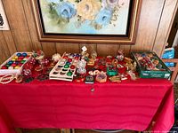 Overview of entire lot on red tablecloth showing variety of ornaments and figurines