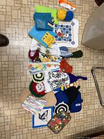 Top-down view showing all microfiber cloths, hand towels, crocheted pot holders, quilted oven mitts and embroidered pot holders laid out on floor
