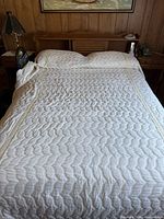 Full-size bed with white quilt, wood headboard with storage