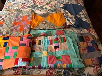 All six vintage quilt tops folded on a bed, showing patterns and colours