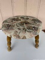 Full view of round tapestry-upholstered stool with three turned wooden legs