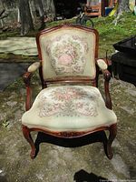 Front view of carved wooden armchair with needlepoint upholstery showing full design and condition