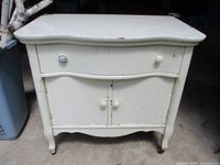 Front view showing drawer, doors, knobs, legs, serpentine top