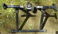 Full view of black indoor bike trainer stand with roller and axle clamps