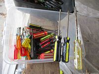 Large clear bin filled with varied screwdrivers and additional tray on top