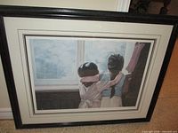Framed limited edition print showing two girls at window, matted under glass in black frame