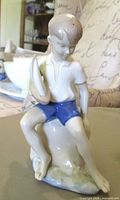 Front view of porcelain boy figurine holding sailboat