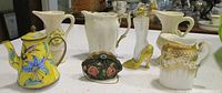 Group shot of all miniatures: enamel teapot, Italian rose pitchers, ivory gilt pitcher, gold drip pitcher, purse trinket, high-heel perfume bottle