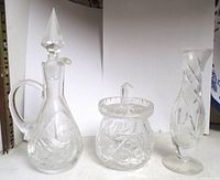 Three crystal pieces: cruet, jam jar with lid, bud vase