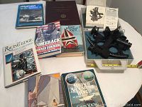 Overall collection showing the sextant, sailing books and case on a table.