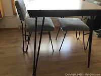 Side view of the retro table showcasing thin black metal tubing legs and wall outlet in background.