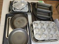 Photo showing various metal baking pans, cookie sheets, loaf and round pans as well as aluminum foil trays stacked