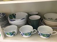 Photo showing matching cups, bowls, and mugs stacked and arranged to display variety and quantity of dinnerware