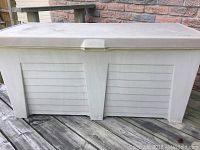 Full exterior view of beige plastic outdoor deck storage box showing side detail and hinged lid.