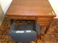 View of solid wood desk with dovetail drawer construction and gray swivel office chair