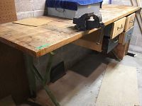 Full view of the solid wood workbench with metal vice and storage drawers, showing the overall structure, tabletop condition, and leg support.
