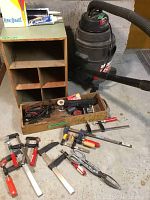 Full view of all items including Shop-Vac with hose and nozzle, clamps, tin snips, caulking gun, wooden storage box, and assorted supplies in a wooden tray on concrete floor.