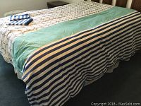King size bed made with feather duvet under a patterned and colored duvet cover with two matching pillow shams folded on top.