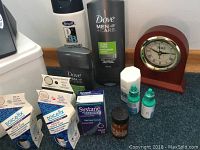 Photo showing bathroom toiletries including Dove Men+Care products, Refresh eye drops, Systane Balance eye drops, Porc-A-Fix porcelain touch-up glaze, and a wooden clock.