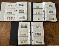 Three open binders displaying multiple album pages filled with British Crown Dependency stamps