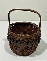 Front view of woven Mi'kmaq basket showing handle and decorative trim