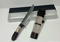 Knife beside matching sheath and box