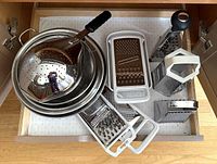 Drawer view showing colanders, scoop strainer, box graters, flat graters
