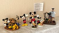 Group shot of six Disney figurines including Animal Kingdom clock, classic Mickey figures, Hunting Mickey, Self Portrait figurine with easel and COA