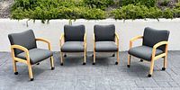 Four gray fabric armchairs with light wood frames and casters