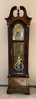 Full front view of grandfather clock showing dial, weights, pendulum and case