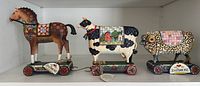 Group shot of horse, cow and sheep pull-toy figurines on shelf