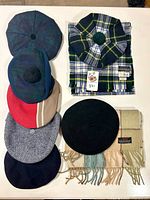 Stack of assorted caps, berets and tams beside two scarves