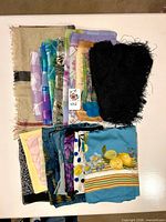 Stack of folded scarves showing variety of prints, colors and lace shawl