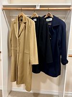Three coats on rack: camel, black, navy