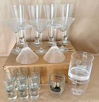 Group of assorted glassware on box: flutes, martini glasses, shot glasses, US Open rocks glasses, two loose martini bowls