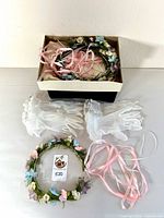 Box containing floral crowns with ribbons and multiple pairs of white sheer gloves