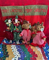Group shot of quilt, two jester dolls, three plush animals, two canvas gift sacks