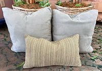 Two sage green square pillows and one striped lumbar pillow front view